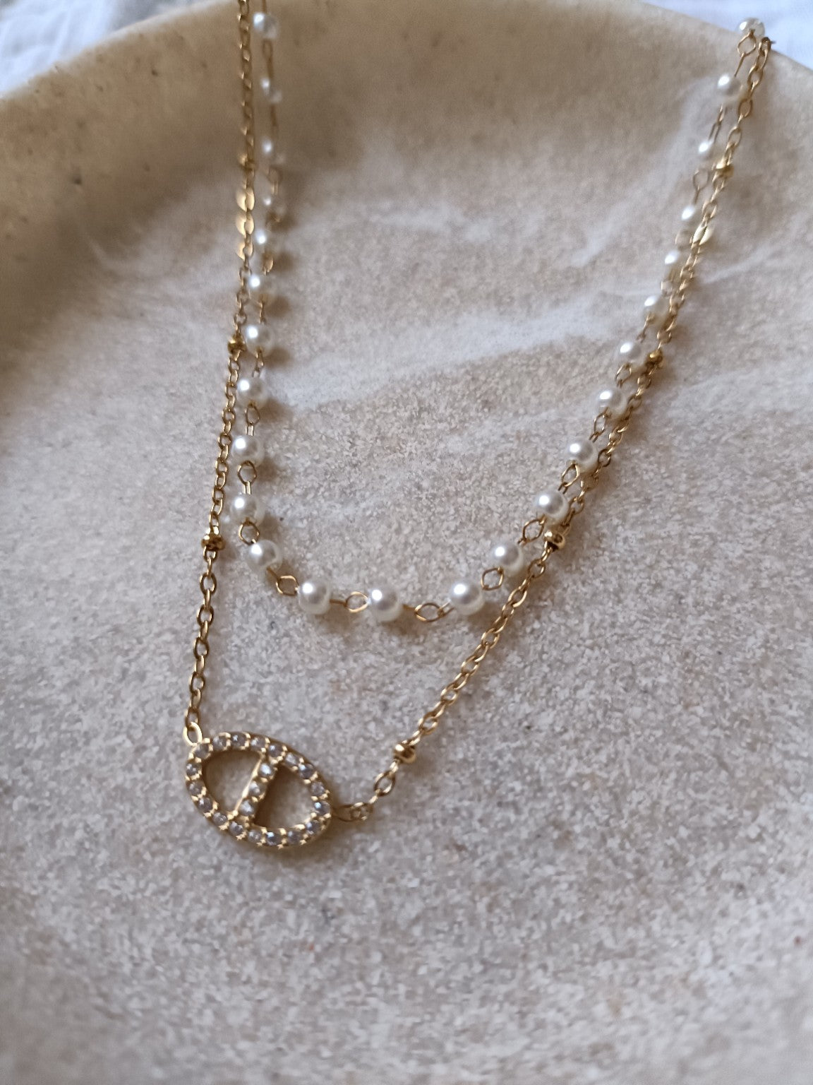 Gros plan sur un collier double doré avec perles fantaisie et pendentif maille marine