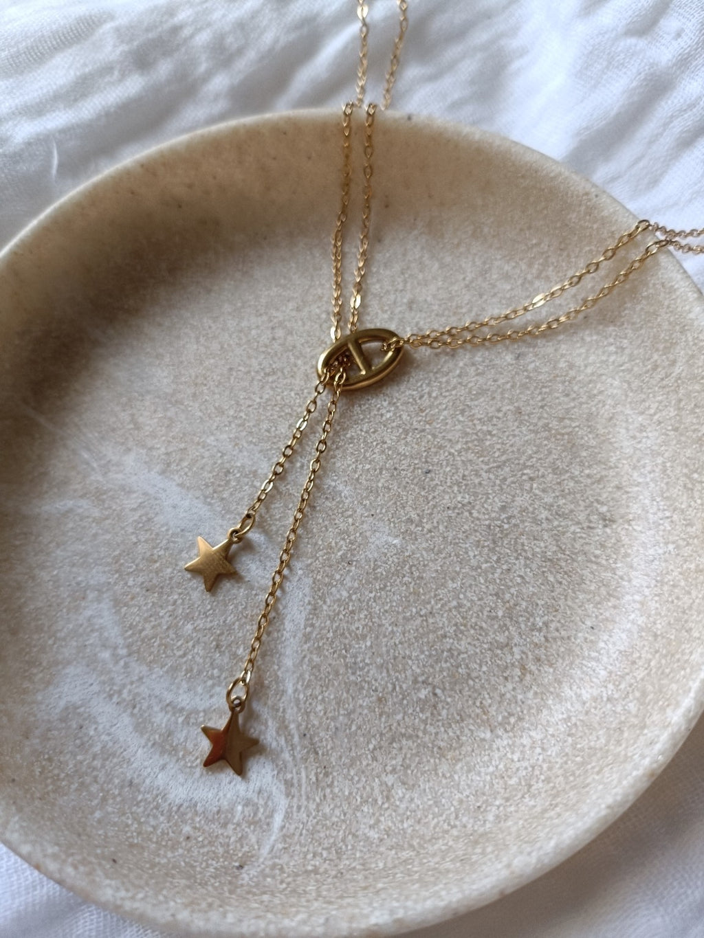 Détail de la maille marine et des étoiles d'un collier double chaîne doré