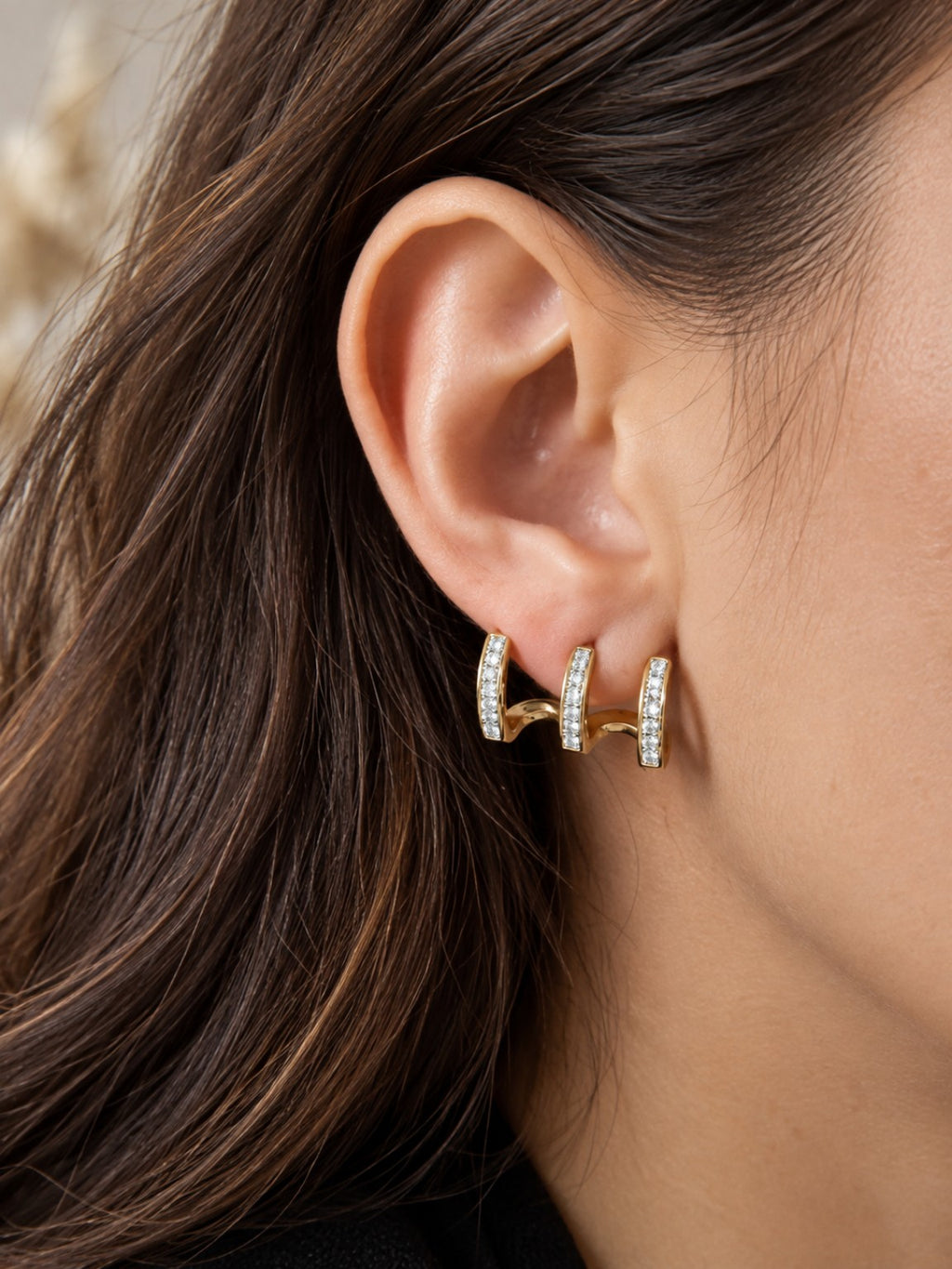 Boucles d'oreilles dorées à 3 anneaux avec strass portées sur une oreille