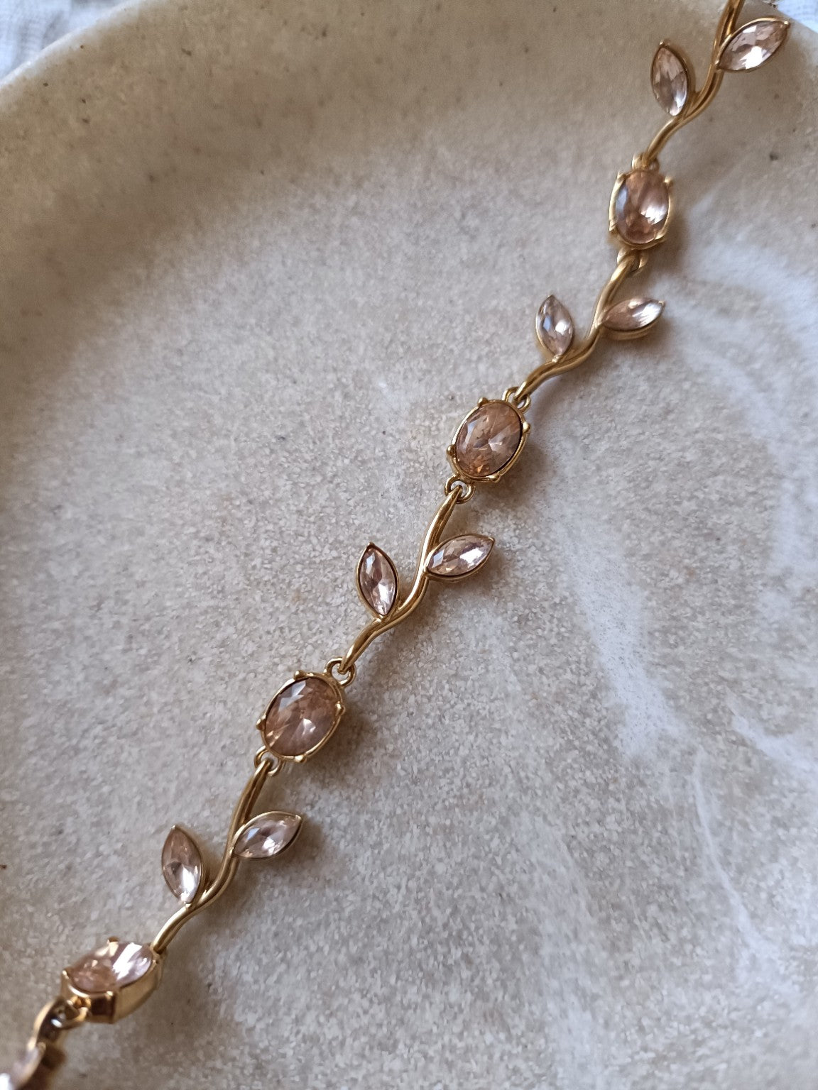 Gros plan sur un bracelet tulipe doré en acier inoxydable avec pierres nude rosées