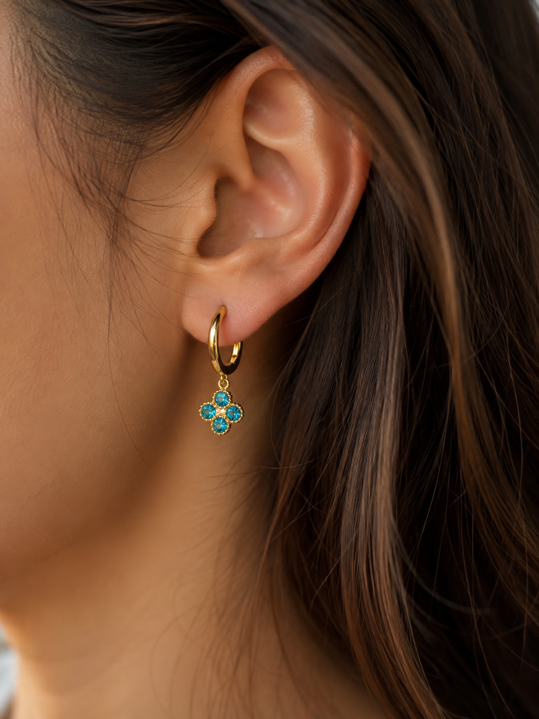 Boucles d'oreilles Trèfle dorées bleues portées par une femme