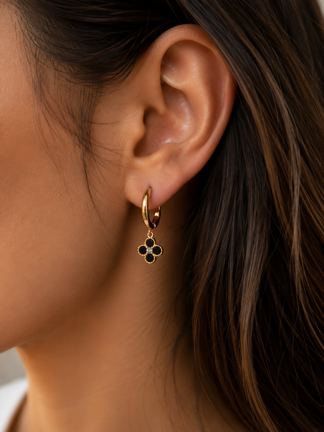 Boucles d'oreilles Trèfle dorées noires portées par une femme